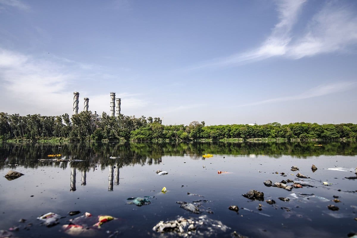 Contaminated and trashed lake with a factory in the background
