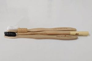 Three different bamboo toothbrushes on a white table