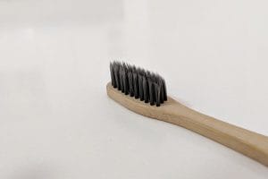 Bamboo toothbrush with dark bristles on a white table