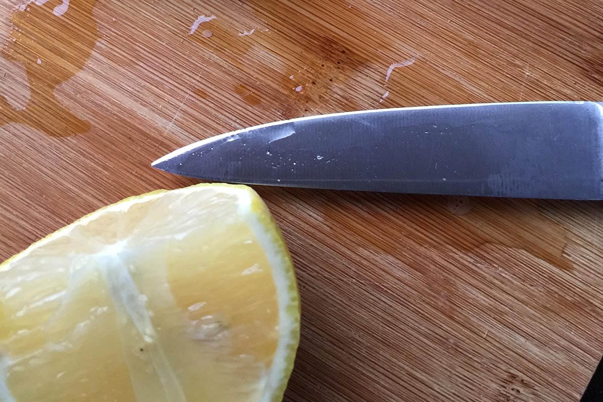 Lemon and knife to clean a bamboo chopping board
