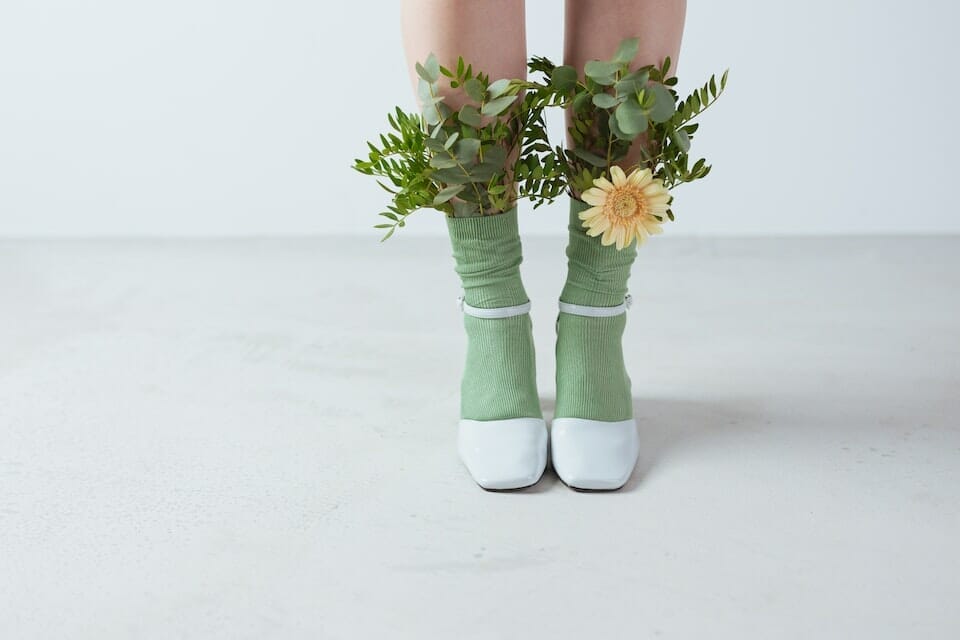 Leaves and a yellow flower on a person's eco-friendly bamboo socks
