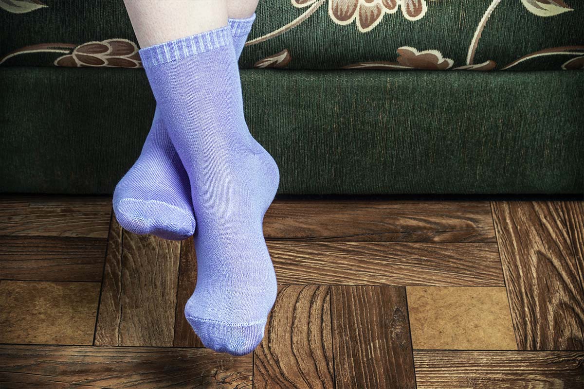 Legs of a person sitting on a green couch wearing purple colored bamboo socks