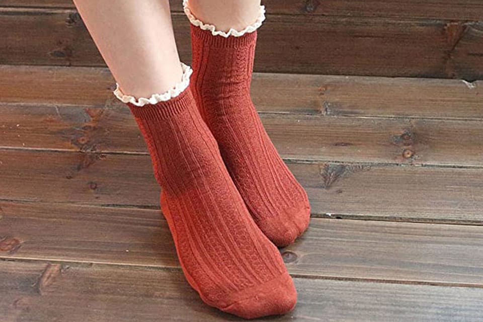 Feet of a person wearing red bamboo socks on a wooden floor 
