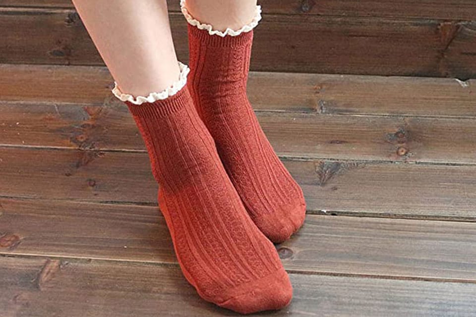 Feet of a person wearing red bamboo socks on a wooden floor 