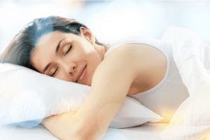 Young women smiles in sleep while her hands under the pillow