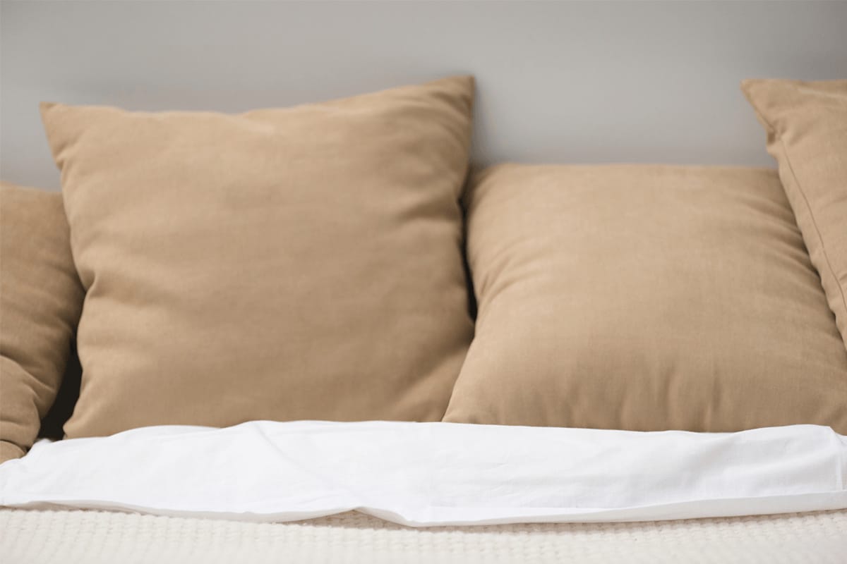Close up of brown pillows on cozy empty bed with text