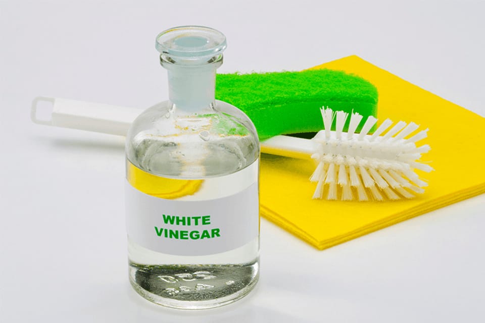 White vinegar in a glass bottle with organic cleaner