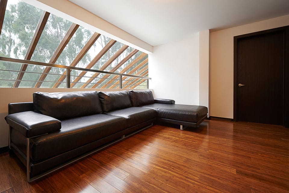 Carbonized bamboo flooring installed in living room with a couch and large windows