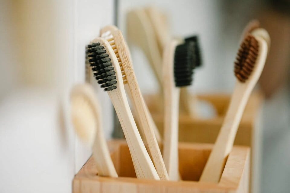 Set of bamboo toothbrushes placed in a wooden box.