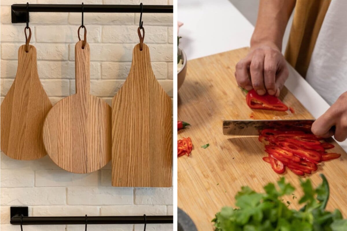 Wood cutting boards hanging in kitchen and a person chopping a red bell pepper on a bamboo cutting board